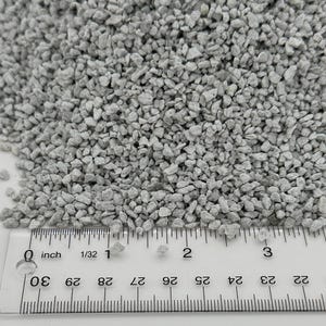 May include: Close-up of small, light gray gravel stones. A ruler with inch measurements is placed at the bottom, showing the scale of the stones. The stones appear to be approximately 1/8 inch in size.