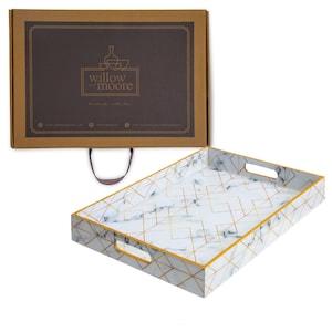 May include: A white serving tray with a gold geometric pattern and a marble effect. The tray has two handles on the sides and a gold trim around the edges. The tray is packaged in a brown box with the text "willow & moore" printed on it.