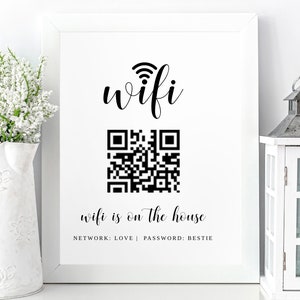 May include: A white framed sign with black text that reads "wifi" with a wifi symbol above the word. Below the word is a black and white QR code. Below the QR code is the text "wifi is on the house" with the text "NETWORK: LOVE | PASSWORD: BESTIE" below that.