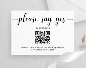 May include: White card with black text that says "please say yes" and "By 10/22/2023". A black and white QR code is below the text. The text below the QR code says "Please scan to RSVP to our wedding website. www.annandoliver.com"
