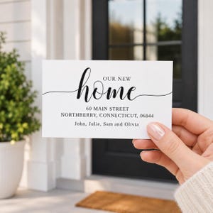 May include: A rectangular white card featuring black text that reads Our New Home, followed by the address 60 Main Street, Northberry, Connecticut, 06844, and the names John, Julie, Sam and Olivia printed in a clean, professional font style.