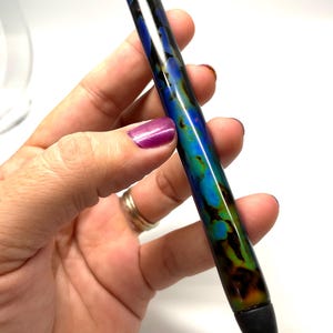 May include: A blue, green, and black pen with a silver clip and a black rubber tip.