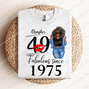 May include: White t-shirt with black text that reads "Chapter 49 Fabulous since 1975". A red lipstick print is above the number 49. A cartoon illustration of a woman with black hair and a denim jacket is to the left of the text.