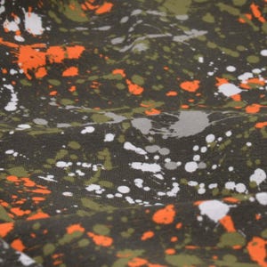 May include: A dark green fabric with a splatter pattern of white, orange, and gray paint.