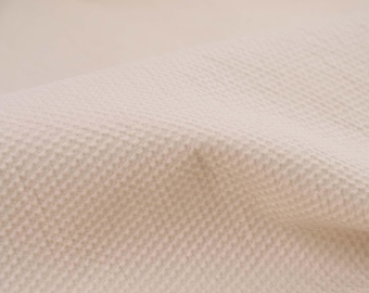May include: Close-up of a textured, off-white fabric with a subtle woven pattern.