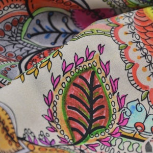 May include: A beige fabric with a colourful paisley pattern. The pattern features intricate details and a variety of colours, including pink, red, green, blue, and yellow.