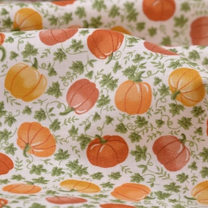 Peut inclure: Gros plan sur un tissu avec un motif répété de citrouilles orange et jaunes avec des vignes et des feuilles vertes sur un fond blanc. Les citrouilles varient en taille et en teinte, créant un thème de récolte d'automne.