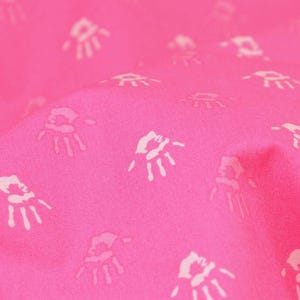 May include: Pink fabric with a white handprint pattern.