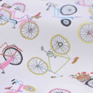Könnte beinhalten: Weißer Stoff mit einem sich wiederholenden Muster aus bunten Fahrrädern. Die Fahrräder sind in verschiedenen Stilen und Farben, darunter rosa, blau, grün und rot.