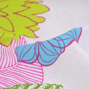 Pode incluir: Tecido branco com um padrão floral rosa, azul e verde. O tecido tem uma superfície texturizada.