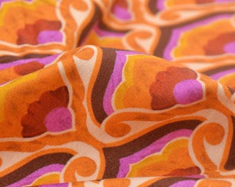 Puede incluir: Primer plano de una tela con un estampado floral retro. El diseño presenta formas arremolinadas en naranja, marrón, rosa y blanco. La tela está doblada, mostrando la textura y profundidad del material.