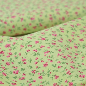 Op de afbeelding: Een groene stof met een klein roze bloemenpatroon.