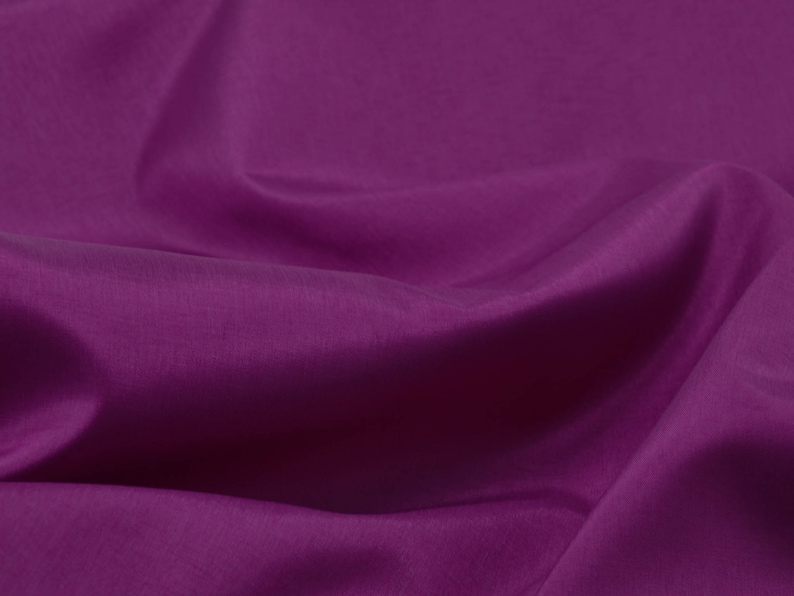 May include: A close-up of a smooth, deep purple fabric with soft folds and wrinkles.