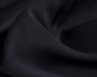 May include: Close-up of a smooth, dark blue fabric with soft folds and wrinkles.