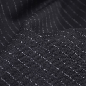 May include: Close-up of a dark grey fabric with a subtle white pinstripe pattern. The fabric is textured and has a slight sheen.