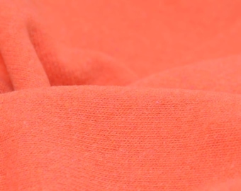Pode incluir: Close-up de um tecido macio de cor coral com uma superfície texturizada.