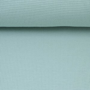 May include: A close-up of a light blue waffle knit fabric. The fabric has a textured surface and a soft, comfortable feel.