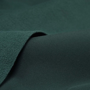 Peut inclure: Gros plan sur deux morceaux de tissu vert foncé, l'un avec une texture duveteuse et l'autre lisse. Le tissu est plié, créant un aspect doux et invitant.