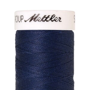 Puede incluir: Una bobina de hilo azul oscuro con una etiqueta blanca que dice "GROUP Mettler S".