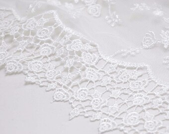 May include: White lace trim with a delicate floral pattern. The lace is intricate and detailed, with a soft, flowing texture.