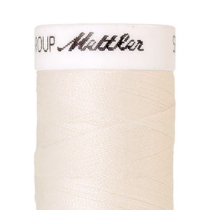 Könnte beinhalten: Eine Spule weißen Fadens mit dem Text "GROUP Mettler" auf dem Etikett.