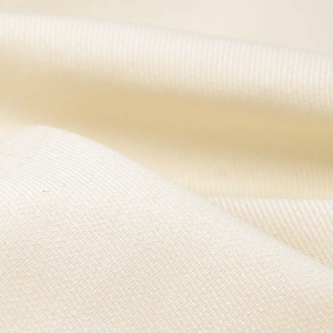 Puede incluir: Primer plano de una tela lisa de color blanco roto con una textura sutil. La tela está doblada y tiene un tacto suave y lujoso.