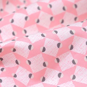 May include: Pink fabric with a white and gray geometric pattern. The pattern features repeating diamonds with half circles inside.