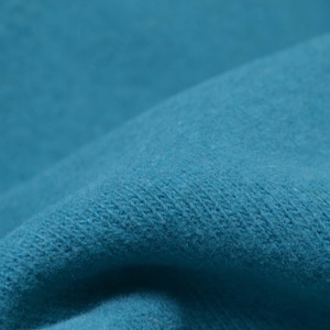 Könnte beinhalten: Nahaufnahme eines weichen, strukturierten Stoffes in leuchtend türkisblauer Farbe. Der Stoff ist gefaltet und hat eine leicht flauschige Oberfläche.