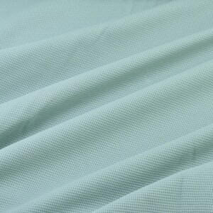 May include: A light blue textured fabric with a smooth, slightly wrinkled surface.