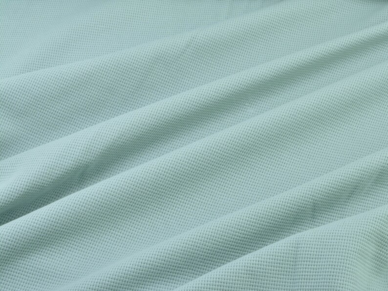 May include: A light blue textured fabric with a smooth, slightly wrinkled surface.
