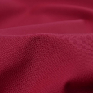 Puede incluir: Primer plano de una tela rojo oscuro con una textura sutil. El material está drapeado, creando pliegues y sombras suaves. El color intenso y el aspecto liso sugieren un textil de alta calidad, adecuado para ropa o decoración del hogar.