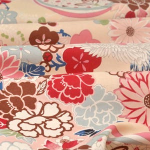 May include: A beige fabric with a floral pattern. The flowers are in shades of pink, red, blue, and brown. The fabric has a soft, flowing texture.