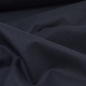 Puede incluir: Primer plano de una tela azul oscuro con un sutil patrón texturizado. La tela está doblada y drapeada, mostrando su textura suave y lisa.