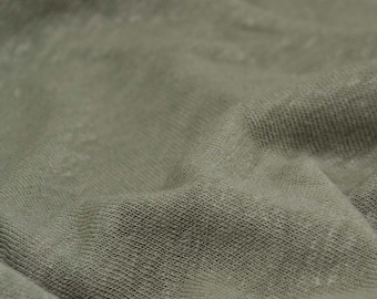 May include: Close-up of a soft, textured, green fabric. The fabric has a subtle, woven pattern.