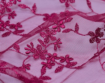 May include: Burgundy lace fabric with a delicate floral pattern. The lace is sheer and has a soft, flowing texture.