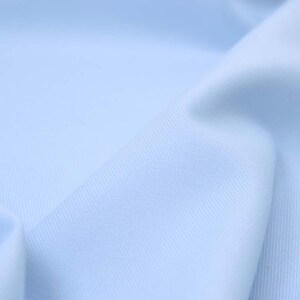 May include: A close-up of a light blue fabric with a subtle texture. The fabric is smooth and soft, with a slight sheen.