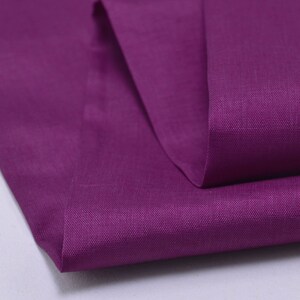 May include: A close-up of a folded piece of purple fabric. The fabric has a smooth, even texture and a subtle sheen.