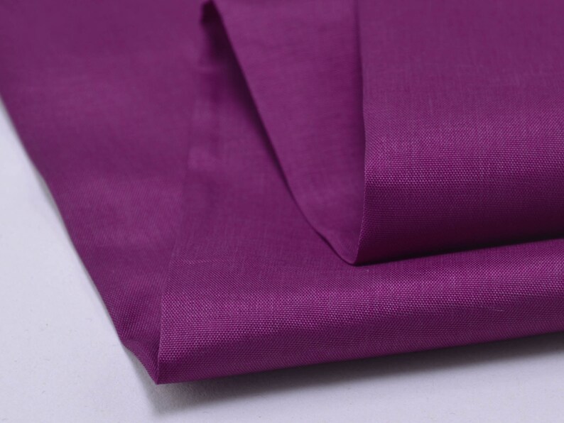 May include: A close-up of a folded piece of purple fabric. The fabric has a smooth, even texture and a subtle sheen.