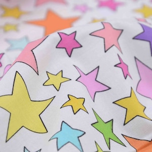 May include: White fabric with a repeating pattern of colourful stars. The stars are outlined in black and filled with various colours, including pink, yellow, blue, green, and orange.