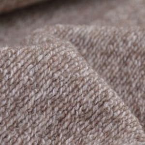 Könnte beinhalten: Nahaufnahme eines braunen und weißen Strickstoffes mit einer strukturierten Oberfläche.