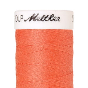 Könnte beinhalten: Eine Spule mit leuchtend orangefarbenem Garn mit dem Text "GROUP Mettler" auf dem Etikett.