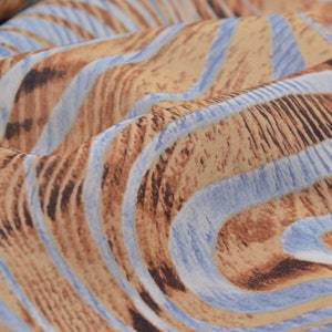 Puede incluir: Primer plano de una tela con un patrón de rayas marrones y azules. La tela tiene un aspecto ondulado y texturizado.