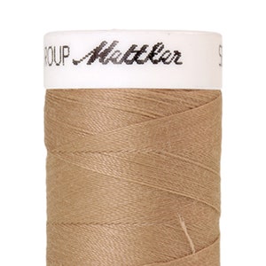 Puede incluir: Una bobina de hilo beige con el texto "GROUP" y "Mettler" en la etiqueta.
