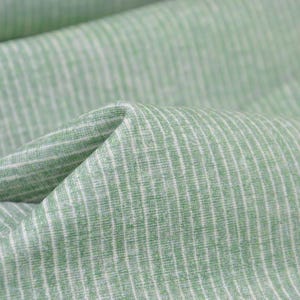 May include: Green and white striped fabric with a subtle texture. The fabric is folded in a way that shows the stripes and texture.