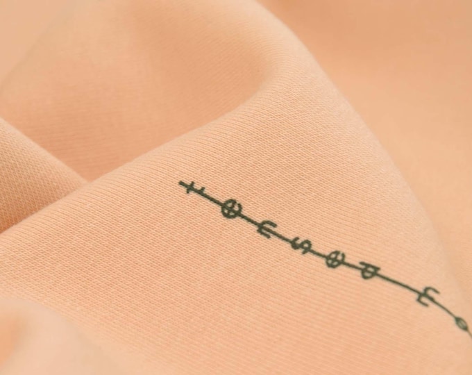 Sweatstoff in apricot mit schwarzen Schriftzügen, aus Baumwolle  - 140cm breit - Stoff zweifarbig, gemustert