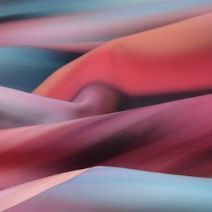 May include: Close-up of a soft, flowing fabric with a gradient of pink, blue, and purple hues. The fabric is draped and folded, creating a textured and abstract pattern.