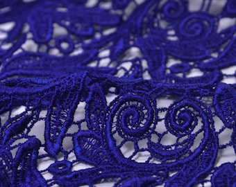 May include: Close-up of a blue lace fabric with a delicate floral pattern. The lace is made of fine threads and has a soft, flowing texture.