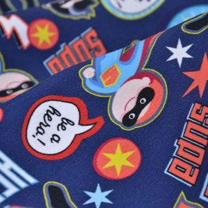 Könnte beinhalten: Blauer Stoff mit einem sich wiederholenden Muster aus Comic-Superhelden, Sternen und den Worten "Super" und "Sei ein Held!"