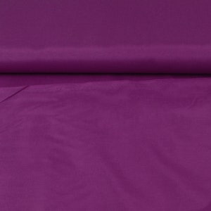 May include: A close-up of a smooth, solid purple fabric. The fabric has a slight sheen and is folded in half.