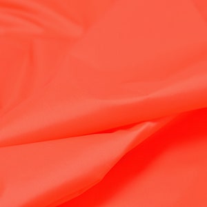May include: Close-up of a bright orange fabric with a smooth, silky texture. The fabric is folded and draped, creating soft, flowing lines.